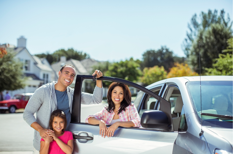 A family in front of the new car that has been delivered to their driveway